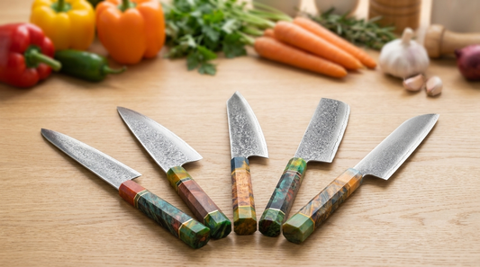 A five-piece Damascus knife set with coloured octagonal handles fanned across an oak worktop